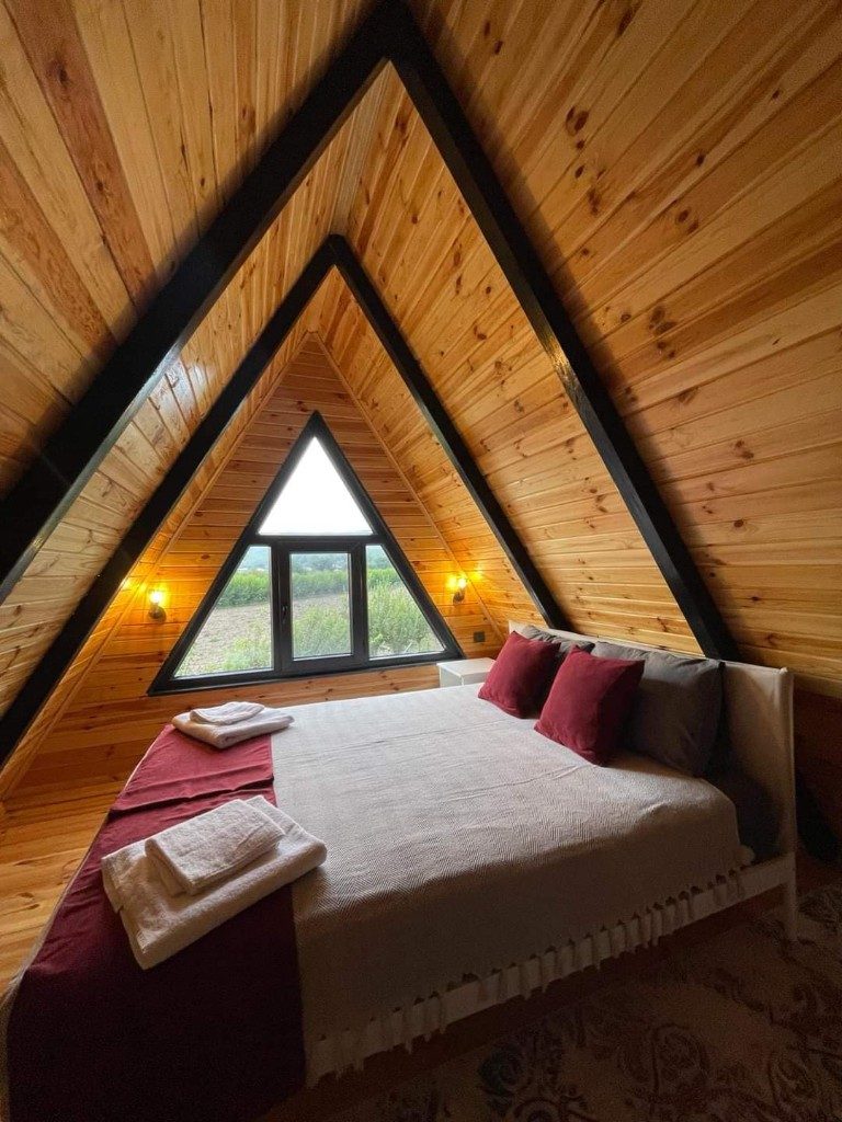A-frame tiny house yatak odası — üçgen pencere ve ahşap tavan